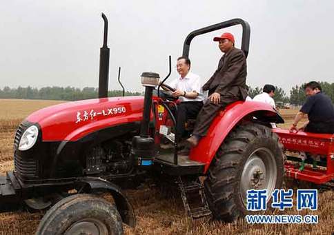 6月10日，在河南省許昌縣陳曹鄉(xiāng)后孫汪村高產(chǎn)小麥示范區(qū)，中共中央政治局常委、國務院總理溫家寶登上一臺“東方紅”牌拖拉機的駕駛室，在司機的指導下掛擋、加油，緊握方向盤，穩(wěn)穩(wěn)地駕駛著，在剛剛收割的麥地里深耕、施肥，種下秋玉米。新華社記者龐興雷攝 