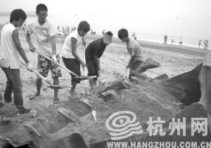 大連市金石灘國賓浴場，工作人員將帶有油污的沙子清理掉。