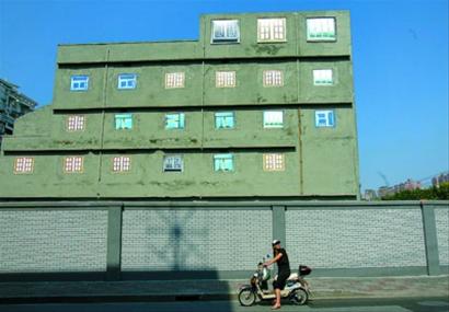 圖片說明：彩色噴繪的窗戶裝點著灰色水泥外墻，荒誕而醒目。